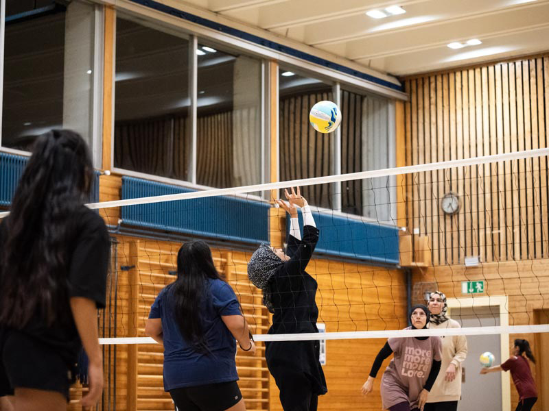 woman in white t-shirt and black leggings sitting on blue and yellow floor